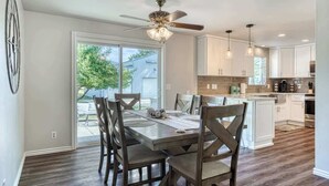 Una cocina moderna con armarios blancos, una isla central y un comedor con mesa y sillas.