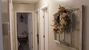 Un pasillo con suelo de madera, paredes blancas y una puerta con un letrero que dice 'welcome'.