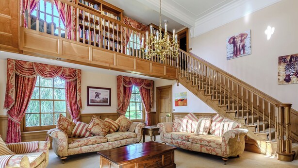 Un vaste salon doté d’un haut plafond, d’un escalier en bois et d’un balcon agrémenté d’étagères à livres.