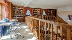 Une bibliothèque avec des étagères, une batterie et un escalier.