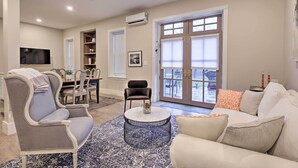 A spacious living room with a sofa, armchairs, a coffee table, and a TV.