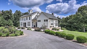 A large, two-story house with a symmetrical facade, a central entrance, and a driveway leading to the front door.