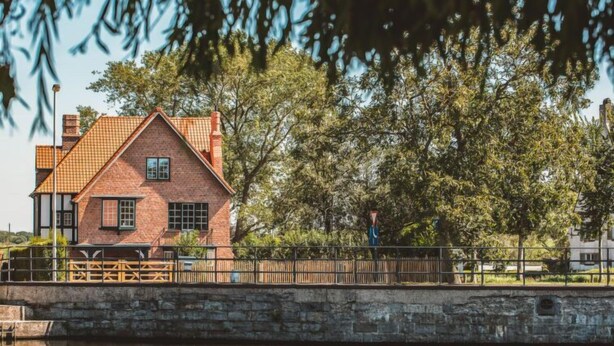 A brick house with a gabled roof, a stone wall, and a wooden fence. - Villa Sas by Interhome (Oudenburg)