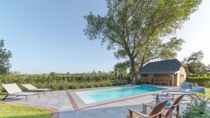 A rectangular swimming pool with a wooden deck and lounge chairs. - Villa Sas by Interhome (Oudenburg)