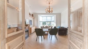 A spacious living room with a large window, a chandelier, and a wooden floor. - Villa Sas by Interhome (Oudenburg)