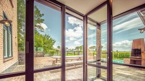 A spacious patio with a brick floor, a wooden table, and a barbecue grill. - Villa Sas by Interhome (Oudenburg)