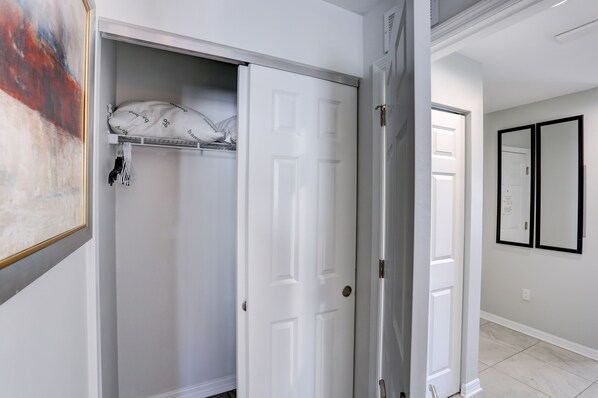 A hallway with a white door, a closet with a hanging organizer, and a framed picture on the wall.
