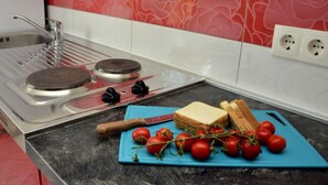 Una cocina con estufa a gas, un lavamanos y una encimera con tabla de cortar, pan y tomates.