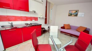 Una cocina moderna con armarios rojos y una mesa de comedor de vidrio con sillas rojas.