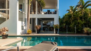 A modern two-story building with a pool, outdoor furniture, and tropical plants. - Sunshine Coast White House (Castaways Beach)