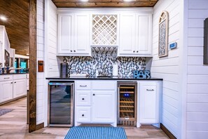 Enjoy cooking in this well-equipped kitchen with a wine cooler, diamond-patterned backsplash, and wooden ceiling.