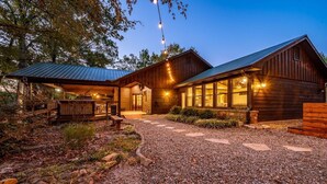 Un chalet rustique avec une allée en gravier, un revêtement extérieur en bois et des guirlandes lumineuses.