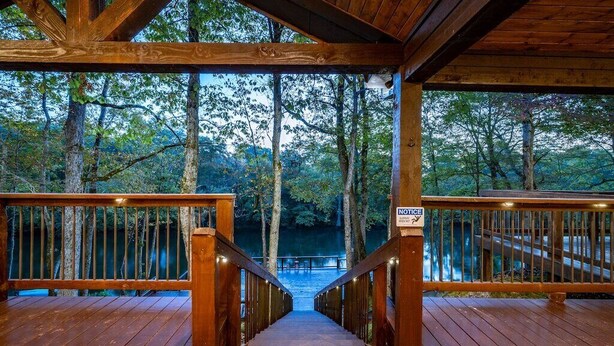 Une terrasse en bois offrant une vue sur une forêt et un plan d’eau.