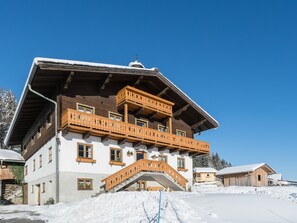 A multi-story wooden building with balconies, a staircase, and a snow-covered ground. - Spacious apartment with a balcony (Wagrain)