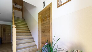 Una escalera de madera que conduce a una habitación con una puerta de madera, una planta en maceta y una rueda decorativa.