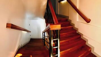 A wooden staircase with a handrail and a light fixture on the wall.