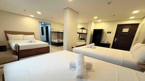 A hotel room with two single beds, a wooden headboard, and a bunk bed. - Belltower Csheli Suites Bantay - Vigan By Zuzu (Bantay)