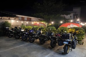 A row of motorcycles parked in a covered area with string lights and umbrellas. - Belltower Csheli Suites Bantay - Vigan By Zuzu (Bantay)