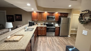 Una cocina moderna con encimeras de granito, electrodomésticos de acero inoxidable y armarios de madera.