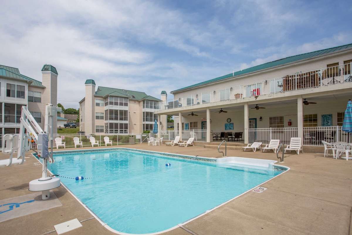 A swimming pool with lounge chairs and a covered patio area.