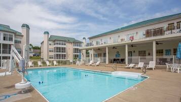 A swimming pool with lounge chairs and a covered patio area.