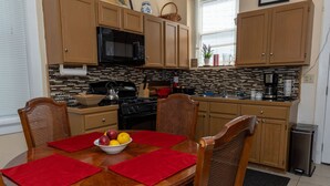 A dining area with a wooden table, four chairs, and a bowl of fruit.