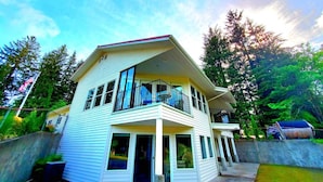 A two-story house with a balcony, a porch, and a garage. - The Cullen's Clair de Lune, River-front Estate (Forks)