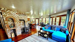 A living room with a brick fireplace, a blue sofa, and a coffee table. - The Cullen's Clair de Lune, River-front Estate (Forks)