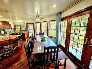 A spacious dining area with a long wooden table, chairs, and a bowl on the table.