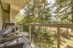 A balcony with a grill, wine glasses, and a bottle of Fort Bere wine. - Woodrun 208 - Ski in Ski out, Common Area Hot Tub & Pool, Gas Fireplace, BBQ (Whistler)