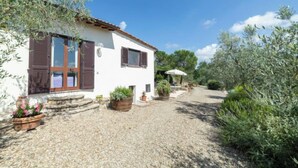 A white building with brown shutters, a gravel driveway, and potted plants. - Vacation home Olivo by Interhome (Castellina in Chianti)