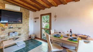 A cozy dining area with a wooden ceiling, stone wall, and a large window. - Vacation home Olivo by Interhome (Castellina in Chianti)
