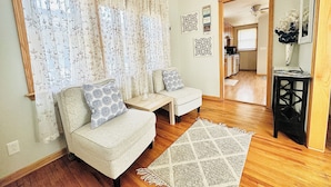 A living room with two sofas, a coffee table, a patterned rug, and a kitchen visible through an open doorway. - St.Paul,Minneapolis,Maplewood,Woodbury Family Home (Saint Paul)