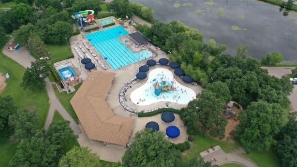 An aerial view of a park with a swimming pool, water slides, and a children's play area. - St.Paul,Minneapolis,Maplewood,Woodbury Family Home (Saint Paul)