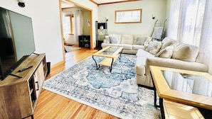A living room with a sofa, coffee table, and TV. There is a wooden floor and a patterned rug. - St.Paul,Minneapolis,Maplewood,Woodbury Family Home (Saint Paul)