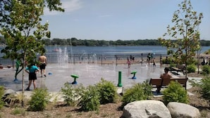 A lakeside park with a fountain, benches, and a walking path. - St.Paul,Minneapolis,Maplewood,Woodbury Family Home (Saint Paul)
