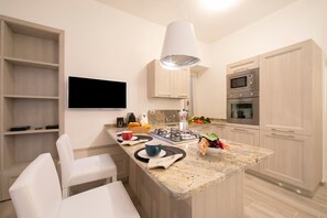 Eine moderne Küche mit Kochinsel, eingebautem Mikrowellenherd, Backofen und einem Wand-Fernseher.