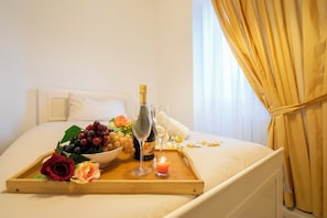 Ein Bett mit einem Tablett Essen, einer Champagnerflasche und Gläsern.