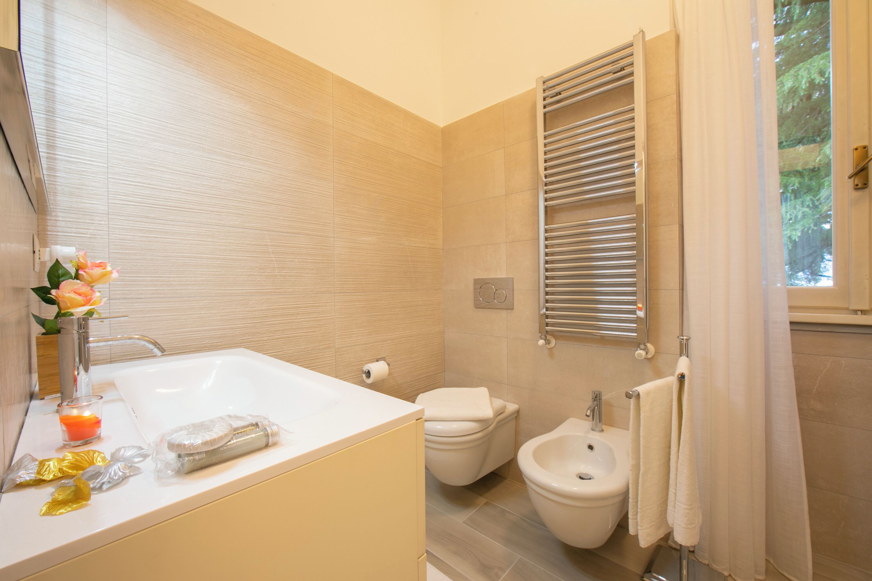 Een moderne badkamer met een badkuip, toilet, bidet en handdoekrek.