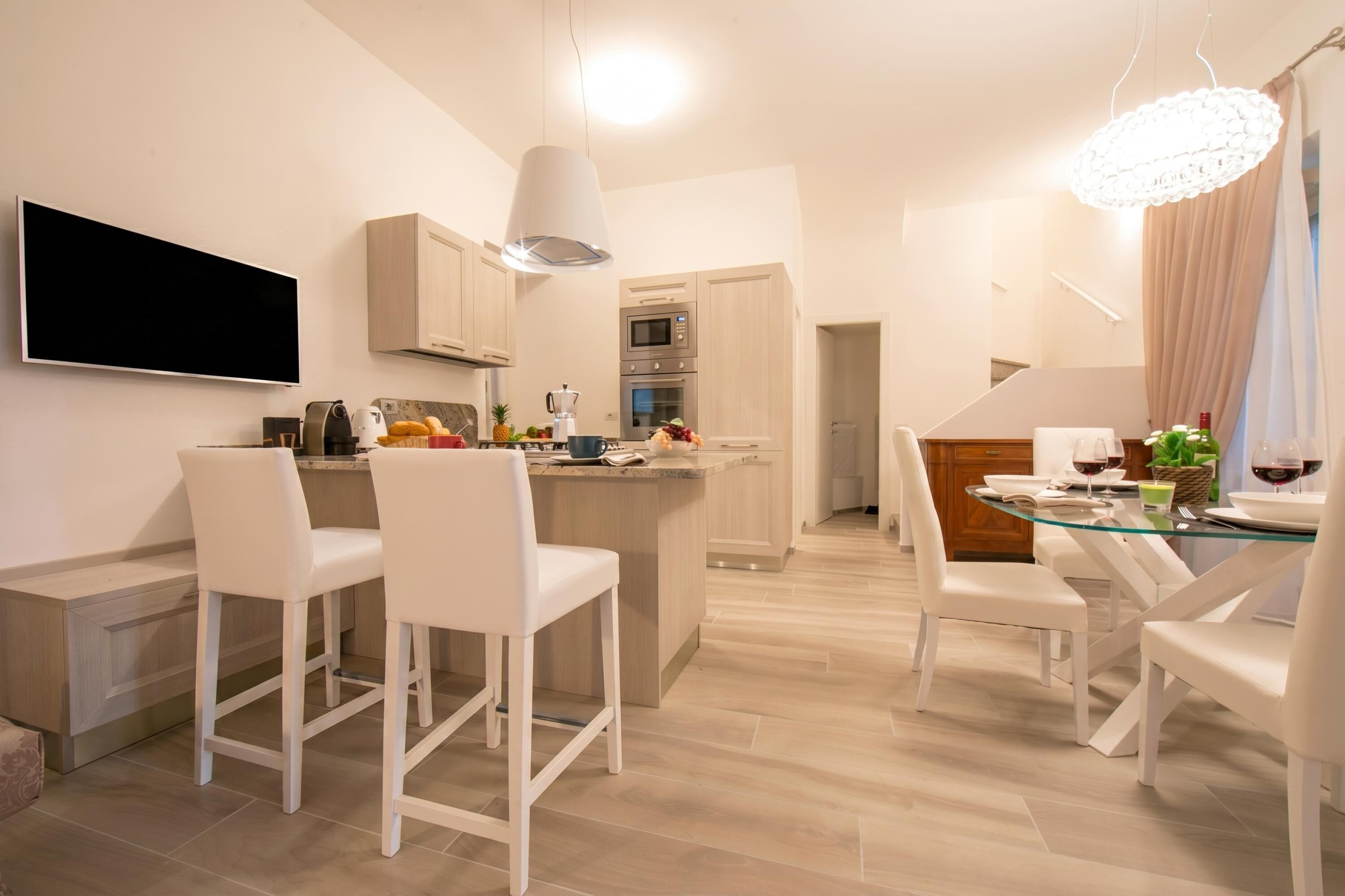 Een moderne keuken met een centraal eiland, barstoelen en een eettafel gedekt voor twee personen.