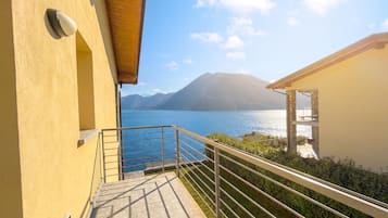 A balcony with a metal railing overlooking a body of water and mountains.