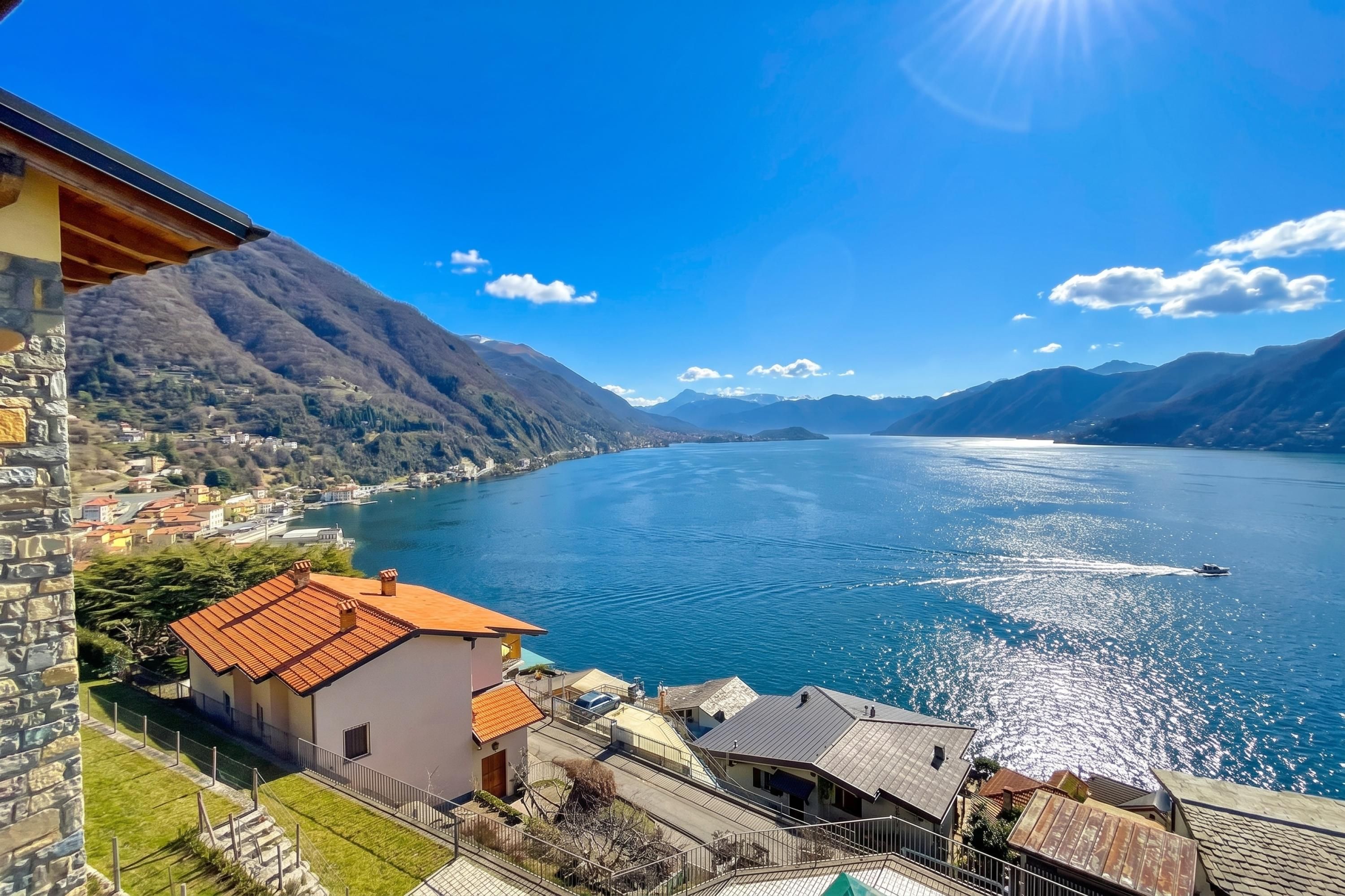 Vista de un lago con montañas al fondo, un pueblo pequeño y un bote en el agua.