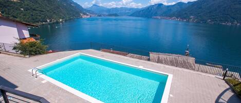 A swimming pool with a view of a lake and mountains.