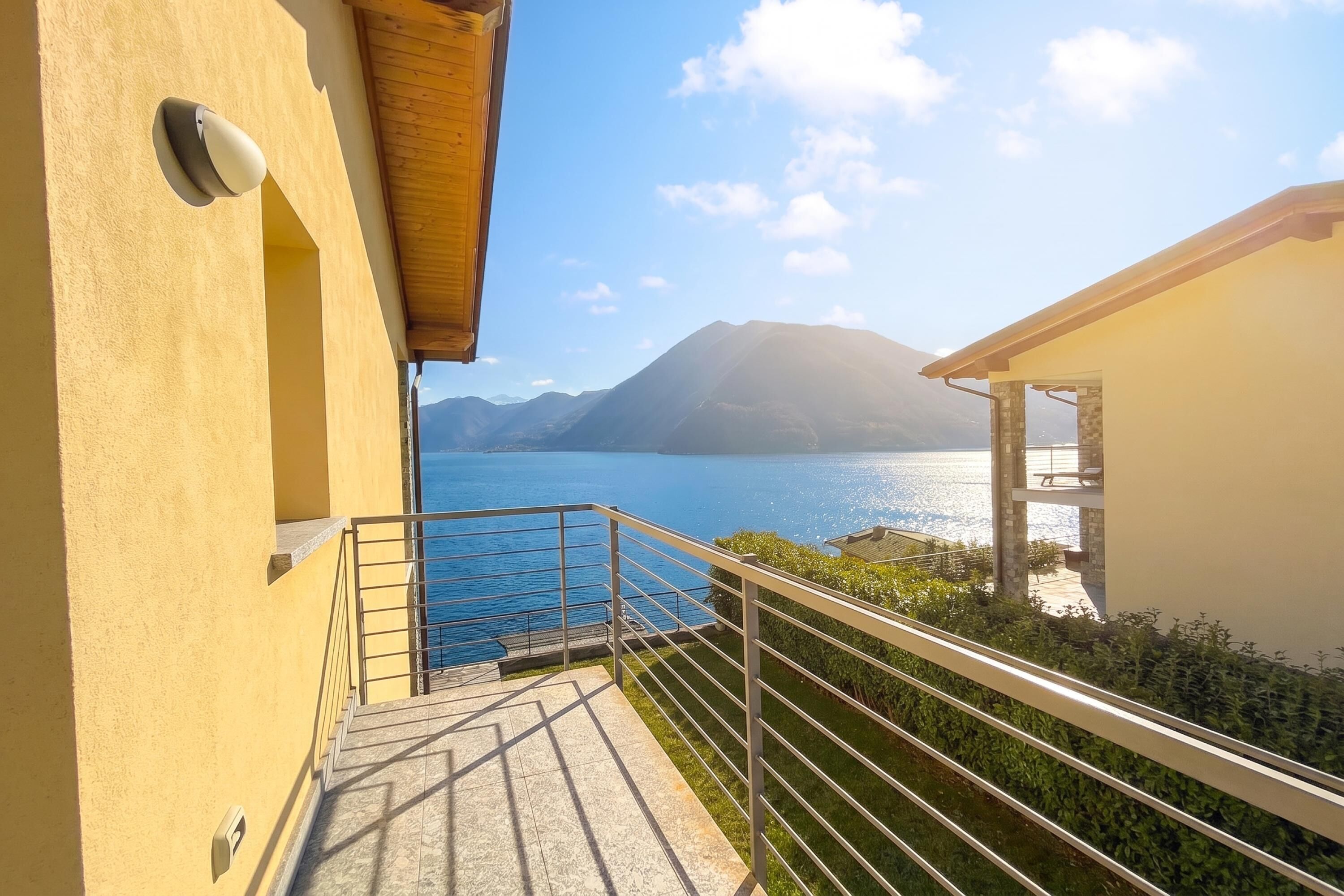 A balcony with a metal railing overlooking a body of water and mountains.