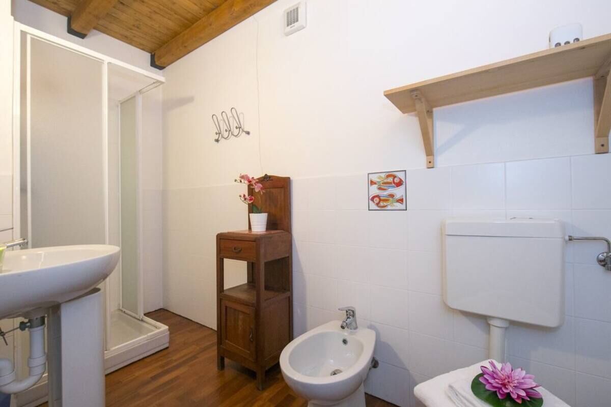 Ein Badezimmer mit Waschbecken, Holzschrank, Bidet und Toilette mit weißem Tank.