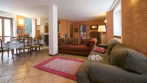 A cozy living room with a sofa, a dining table with chairs, and a kitchen area in the background. - Villa Frassi (Pianello del Lario)