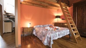 A bedroom with a wooden bed, a nightstand, a dresser, a wooden ladder, and a staircase. - Villa Frassi (Pianello del Lario)