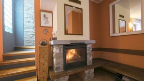 A stone fireplace with a mirror above it, wooden steps leading up to a landing, and a framed picture on the wall. - Villa Frassi (Pianello del Lario)
