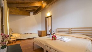 A bedroom with two beds, wooden headboards, a bedside table, a nightstand, a mirror, and a small potted plant. - Casa Simo Lenno (Tremezzina)