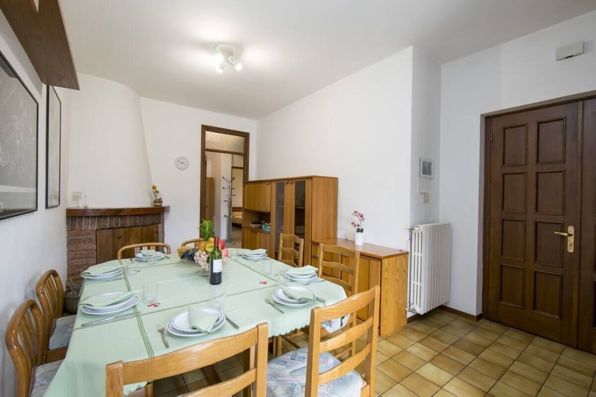 Un coin repas avec une table dressée pour quatre personnes, des chaises en bois, un buffet et une porte.